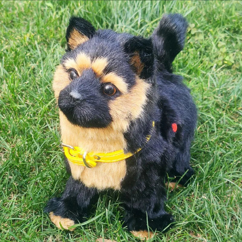 Interactive plush dog toy, black and tan fur, yellow collar, sitting on green grass