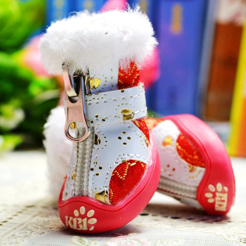 Pet snow boots with white upper, fluffy trim, gold buckles, red outsole, paw print accents