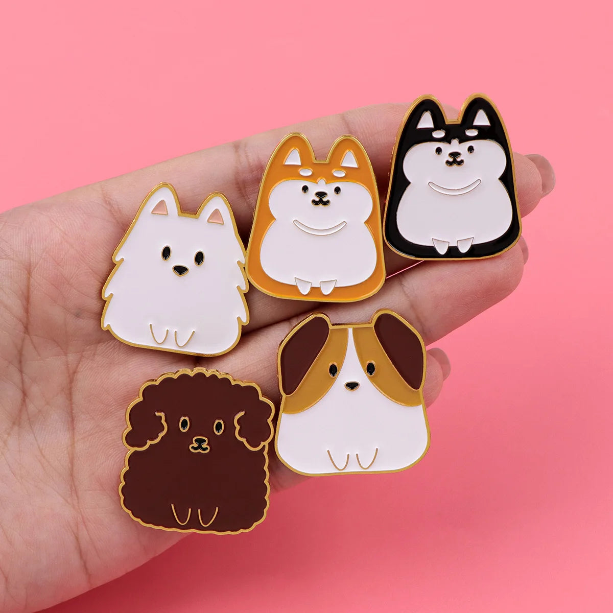 Cat and dog enamel pins on a hand: orange, white, black, and brown designs