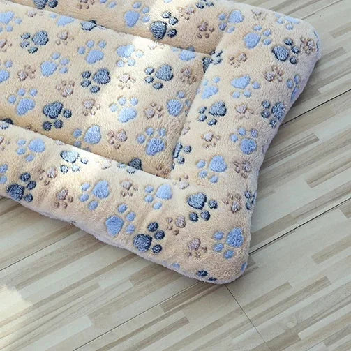 Beige plush pet blanket mat with blue paw-print pattern and soft padded border