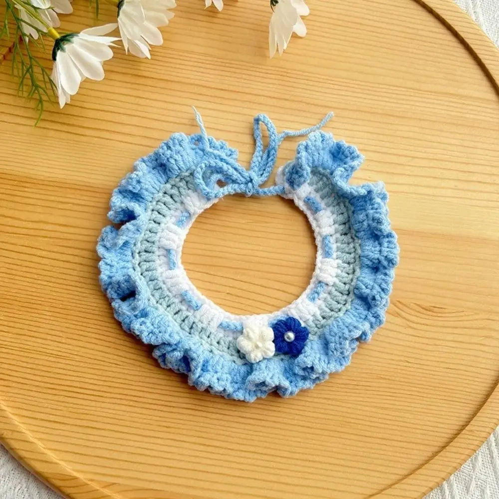 Blue crocheted pet scarf bib with white trim and flower accents, round collar