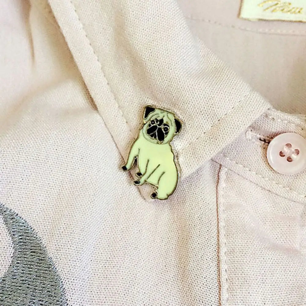 Cartoon dog enamel pin badge on light fabric, black face with green body