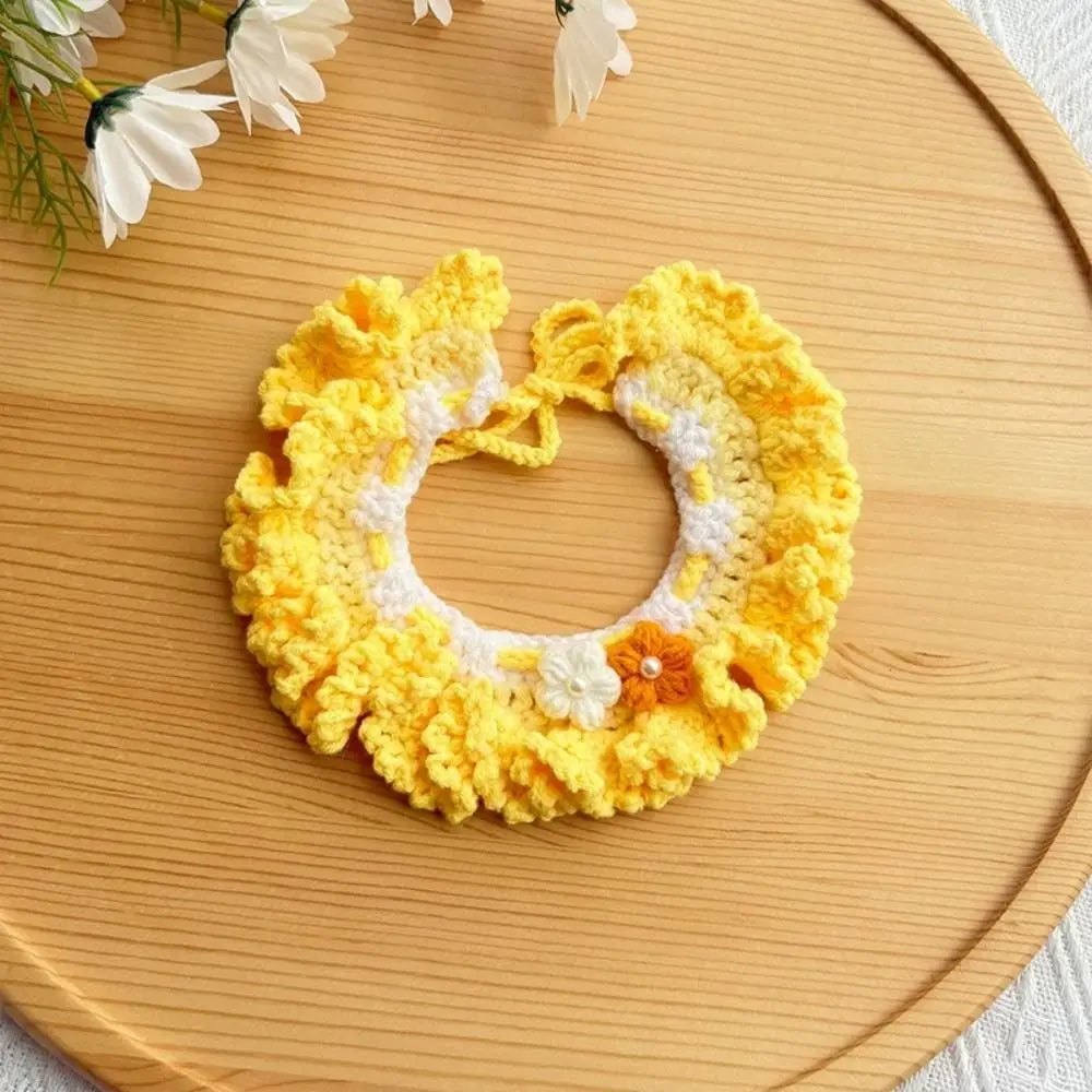 Yellow crocheted pet scarf bib with white trim, orange button, and small flower accents