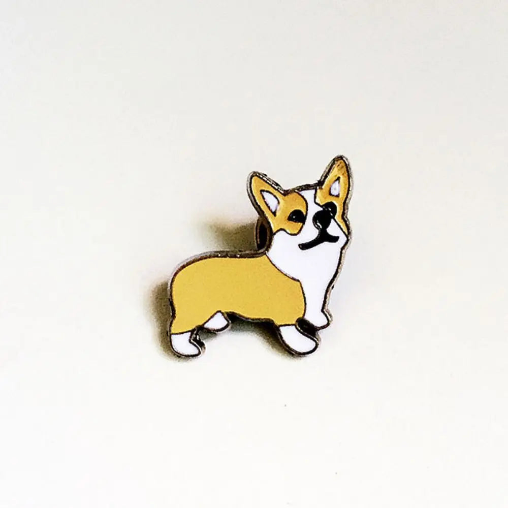 Yellow-and-white cartoon corgi-like dog enamel pin with black outline and silver border