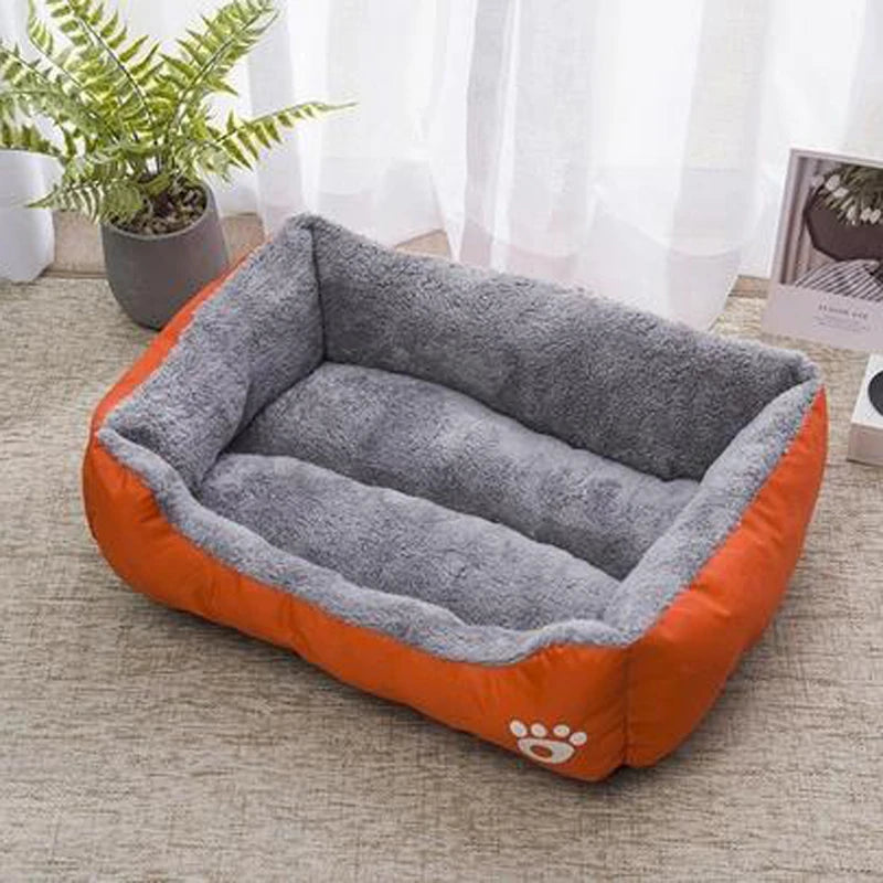 Plush dog bed with gray inner cushion and orange outer base, paw logo on front