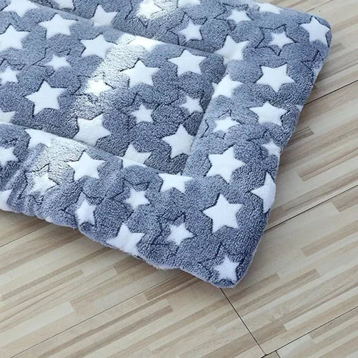Plush washable pet blanket with white star pattern on blue, folded corner