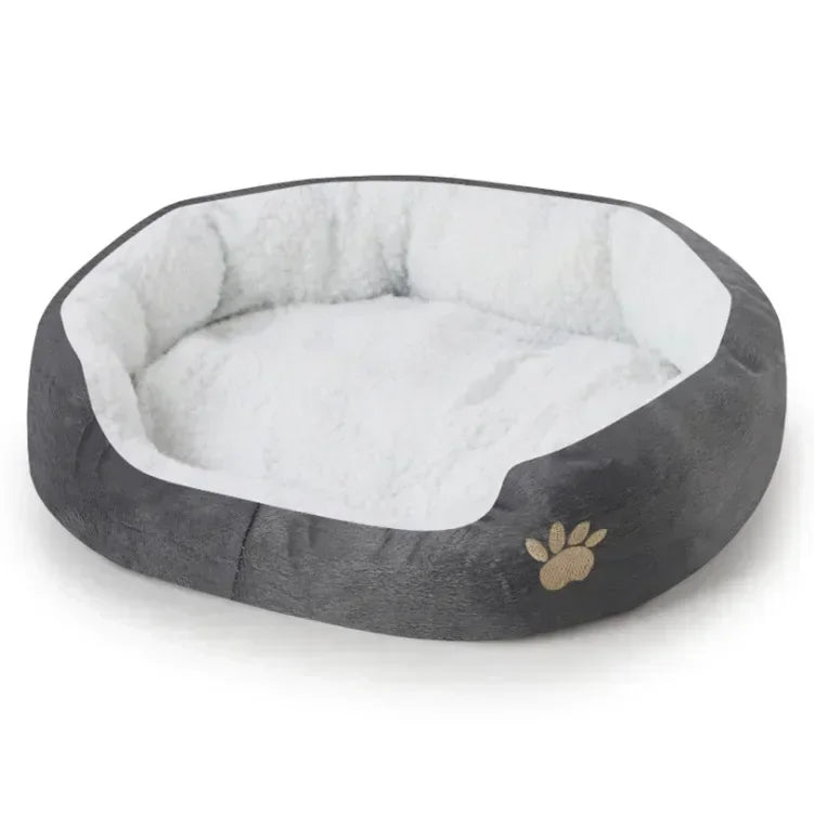 Gray plush oval dog bed with white cushioned center and paw emblem on the side