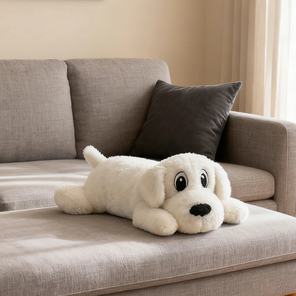 White plush dog toy lying on a gray couch with black nose and eyes