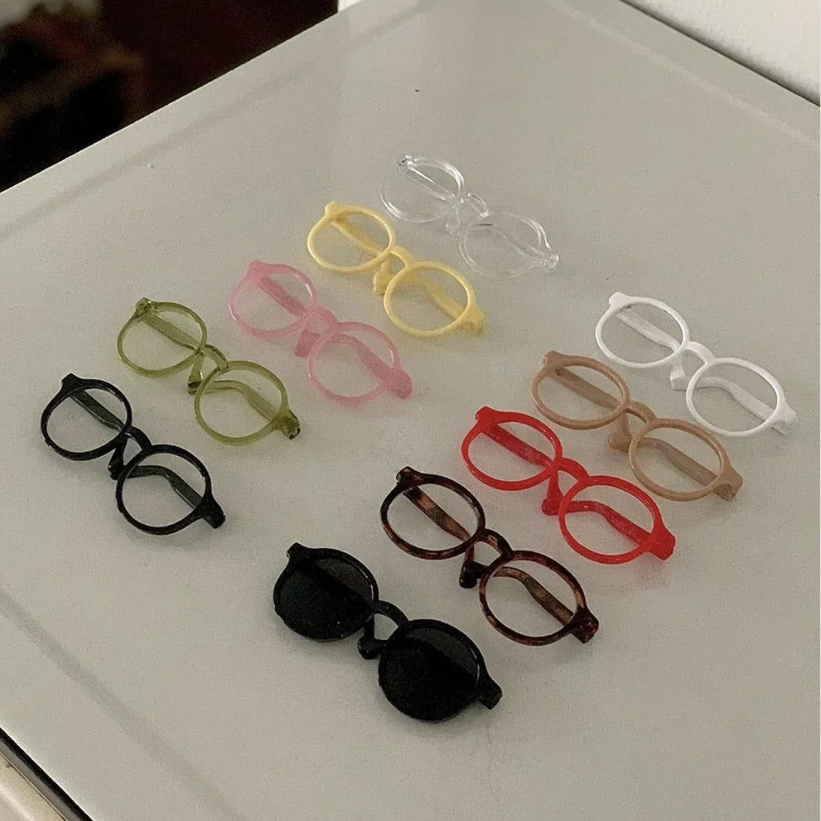 Assorted pet novelty sunglasses in multiple colors laid out