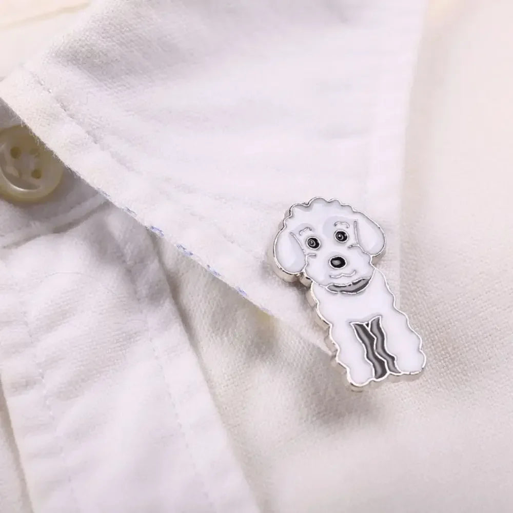Cartoon white dog enamel pin with silver-tone outline and dark eyes, on fabric.