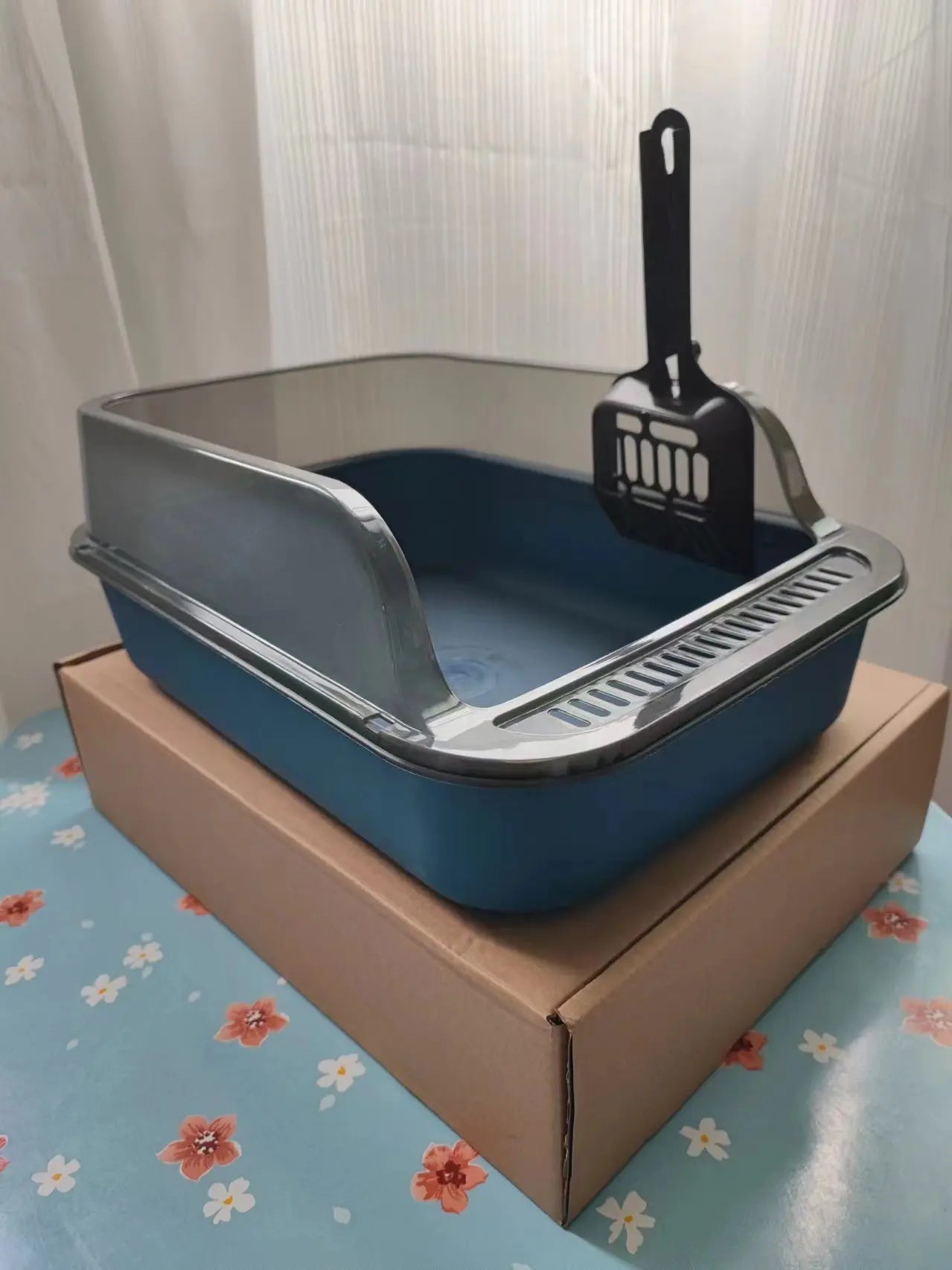Blue semi-enclosed cat litter box with black scoop and silver rake base