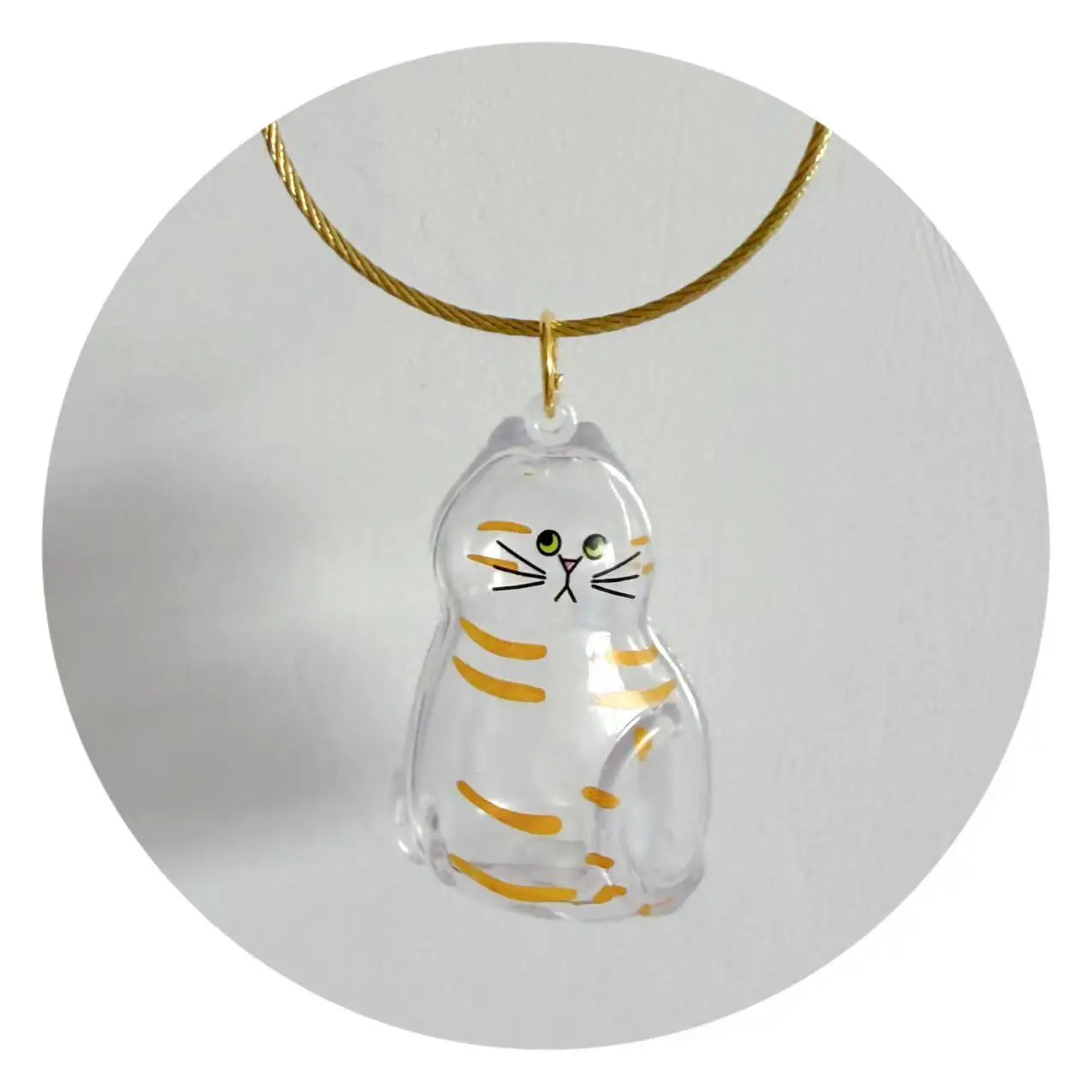 Clear resin cat charm with yellow stripes and a gold cord loop