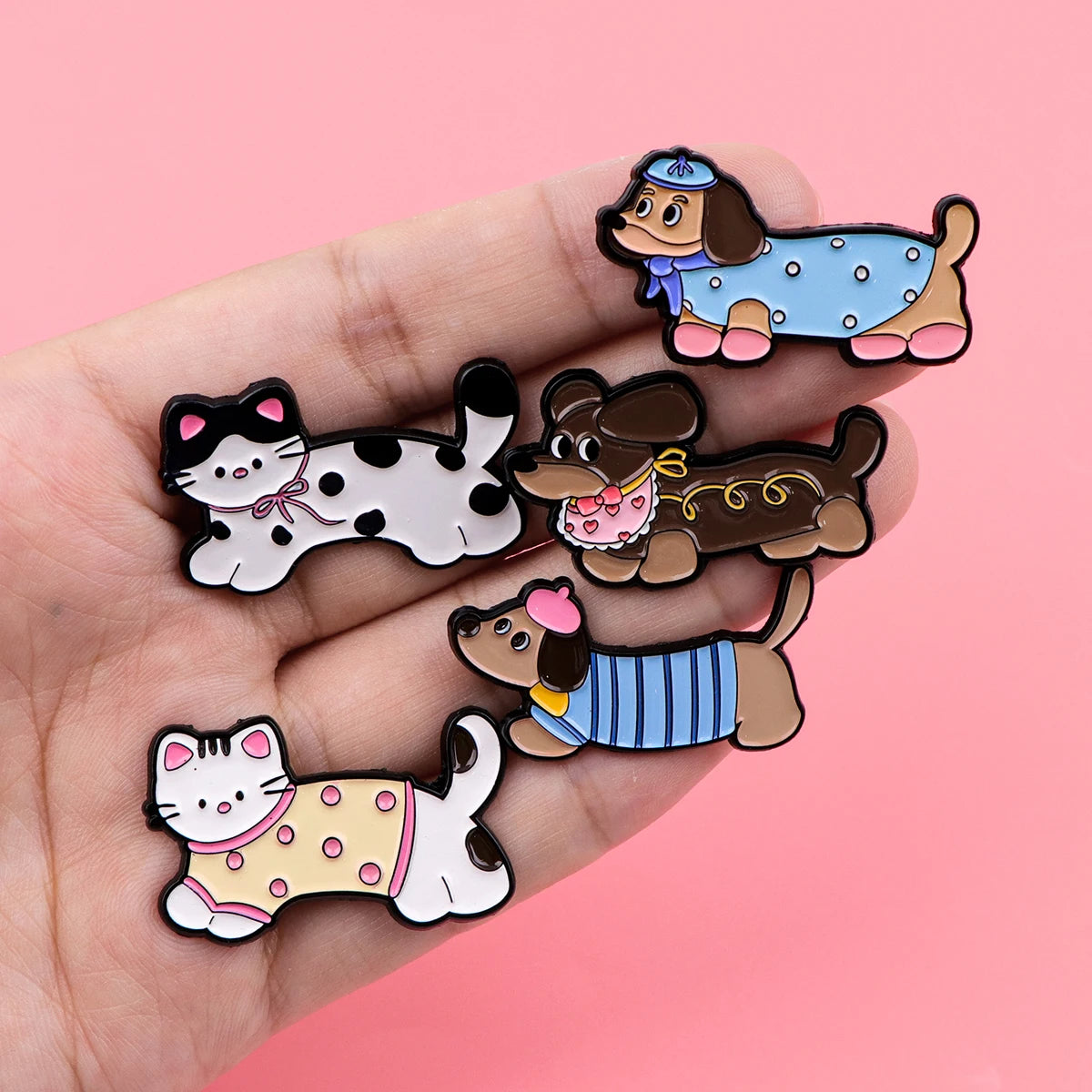 Five dog enamel lapel pins with colorful outfits on a hand