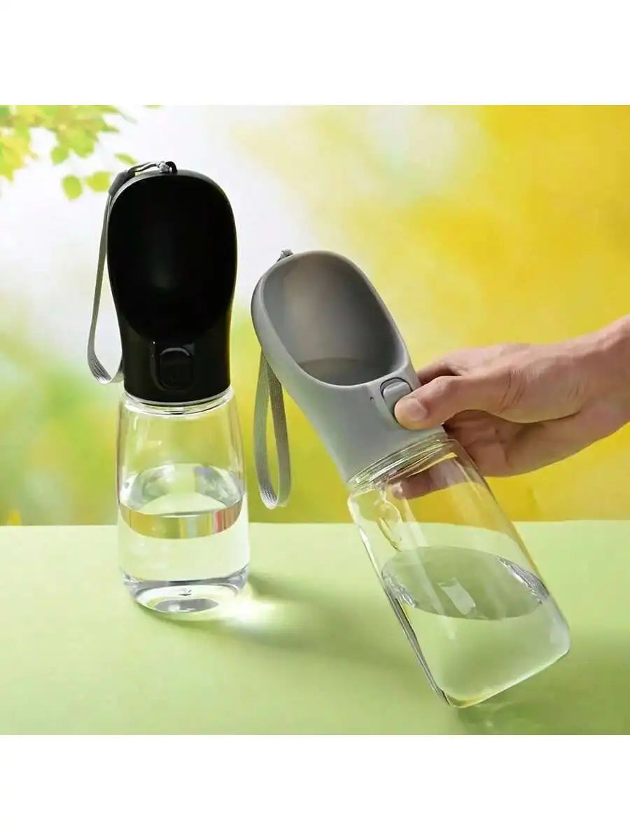 Portable pet water bottle dispenser with clear reservoirs; hand holds gray refill cup
