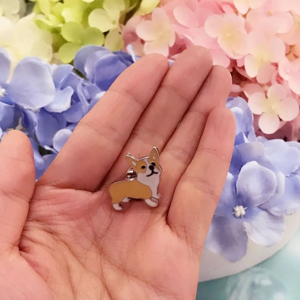 Cartoon dog enamel pin held in hand with tan and white fur