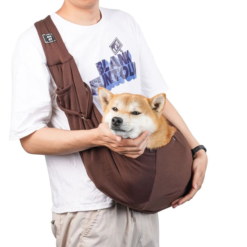 Pet sling bag with shoulder strap, dark brown fabric, holding a small dog.