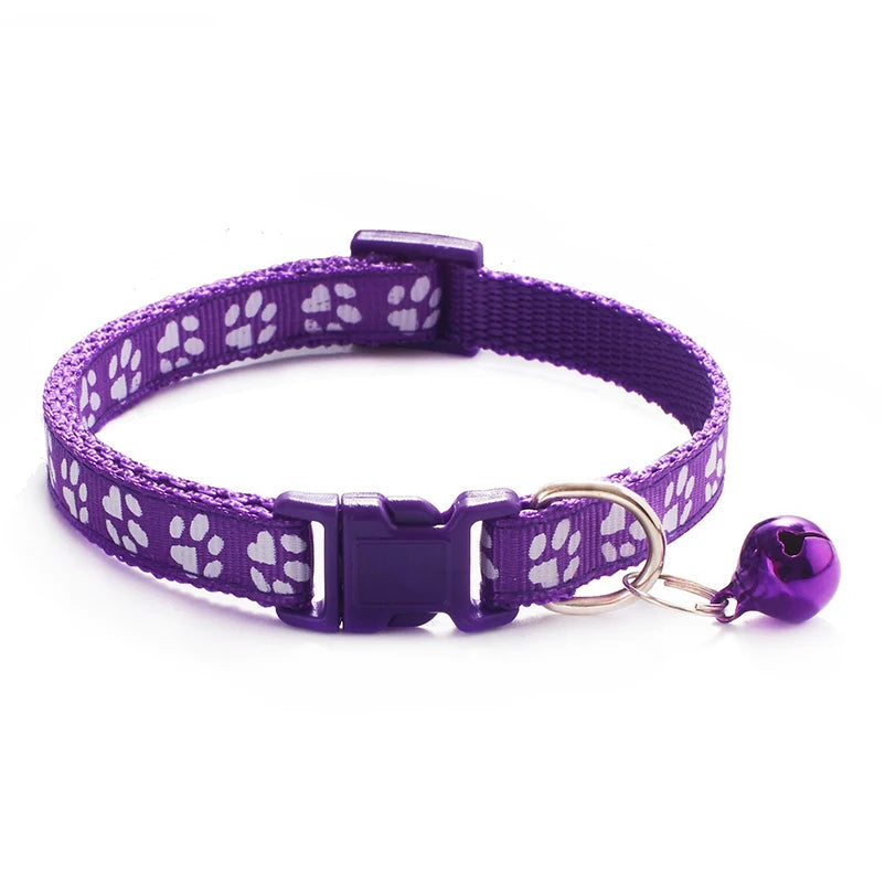Purple paw-print cat collar with plastic buckle and bell charm on a ring