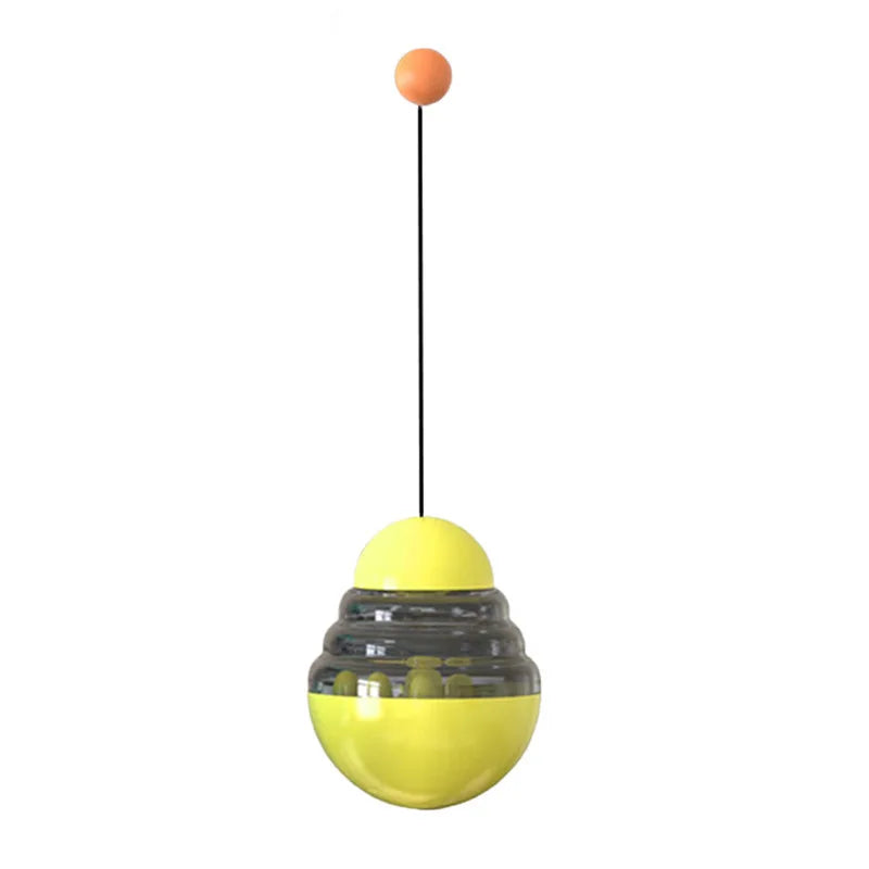 Yellow hanging treat dispensing ball toy with orange knob on a string
