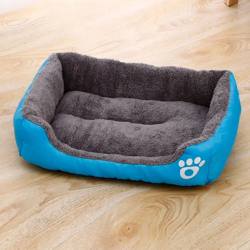 Plush dog bed with gray inner lining and blue outer cushion, paw logo on side