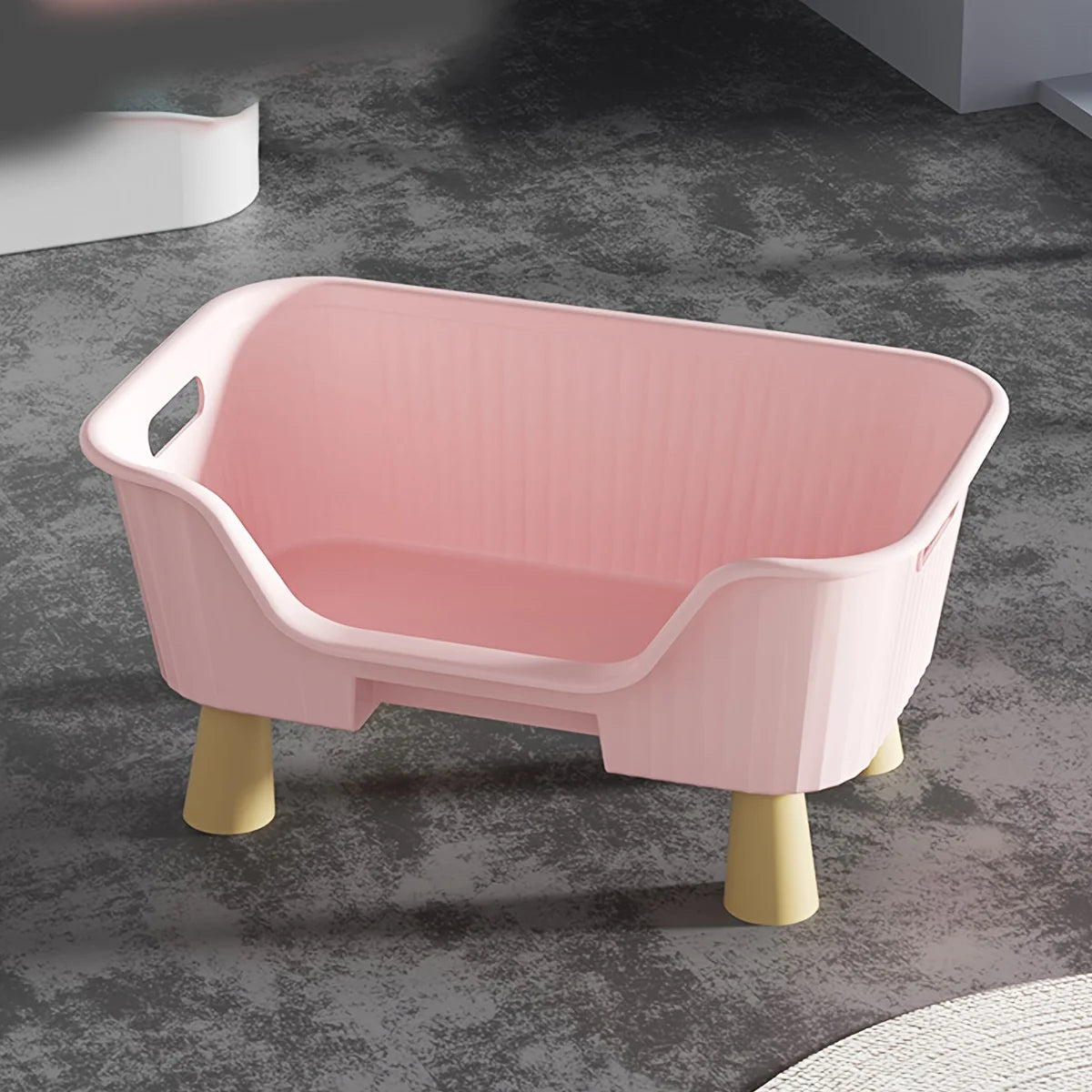 Pink cat bed with white frame and front opening, cushioned sides, on tan legs.
