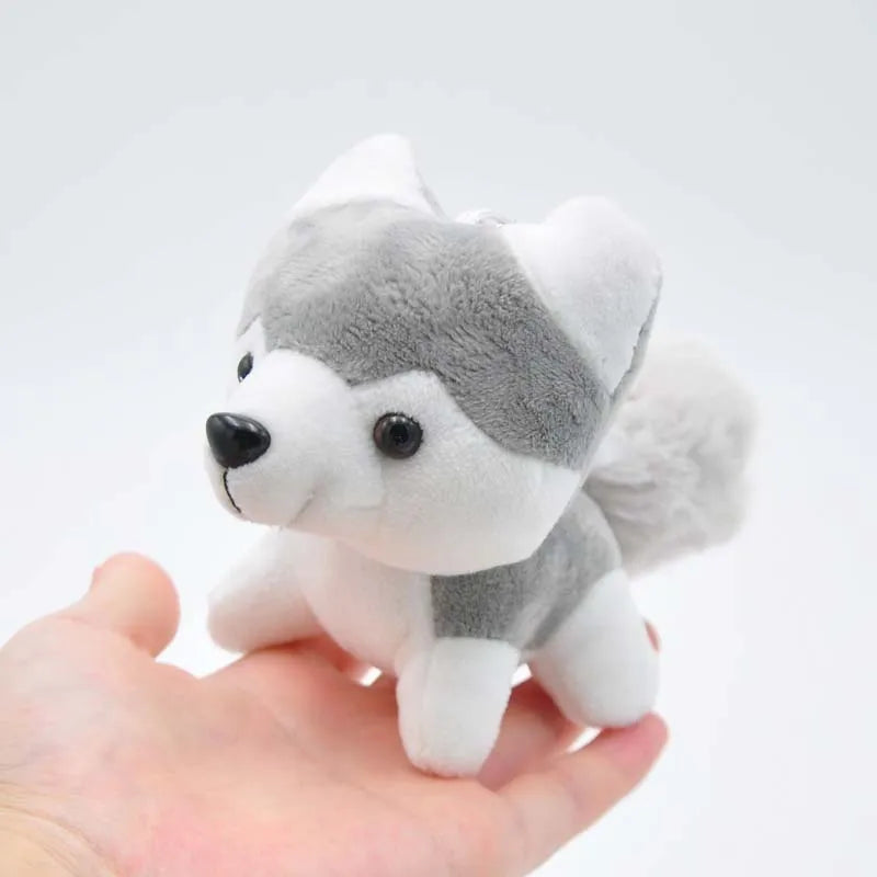 Small gray-and-white husky plush toy in a hand, upright ears and black nose