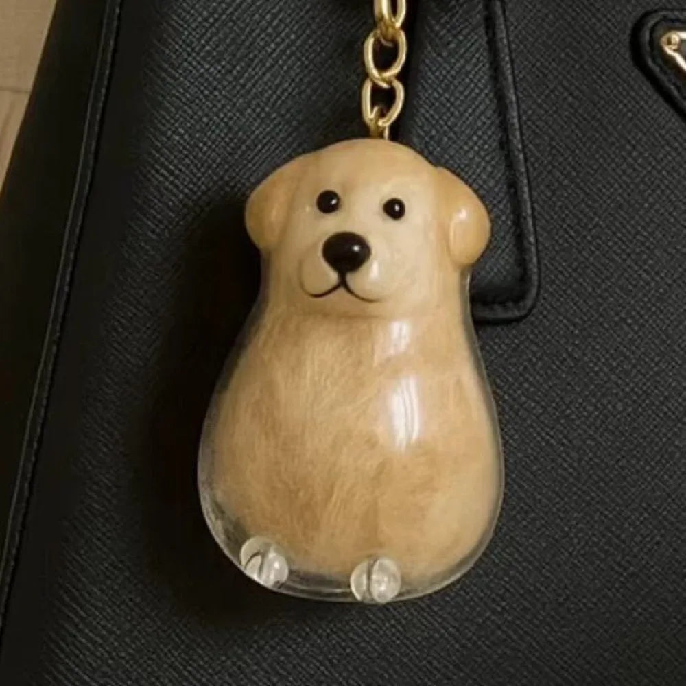 Transparent pet hair memorial keychain capsule with cream-colored dog figurine