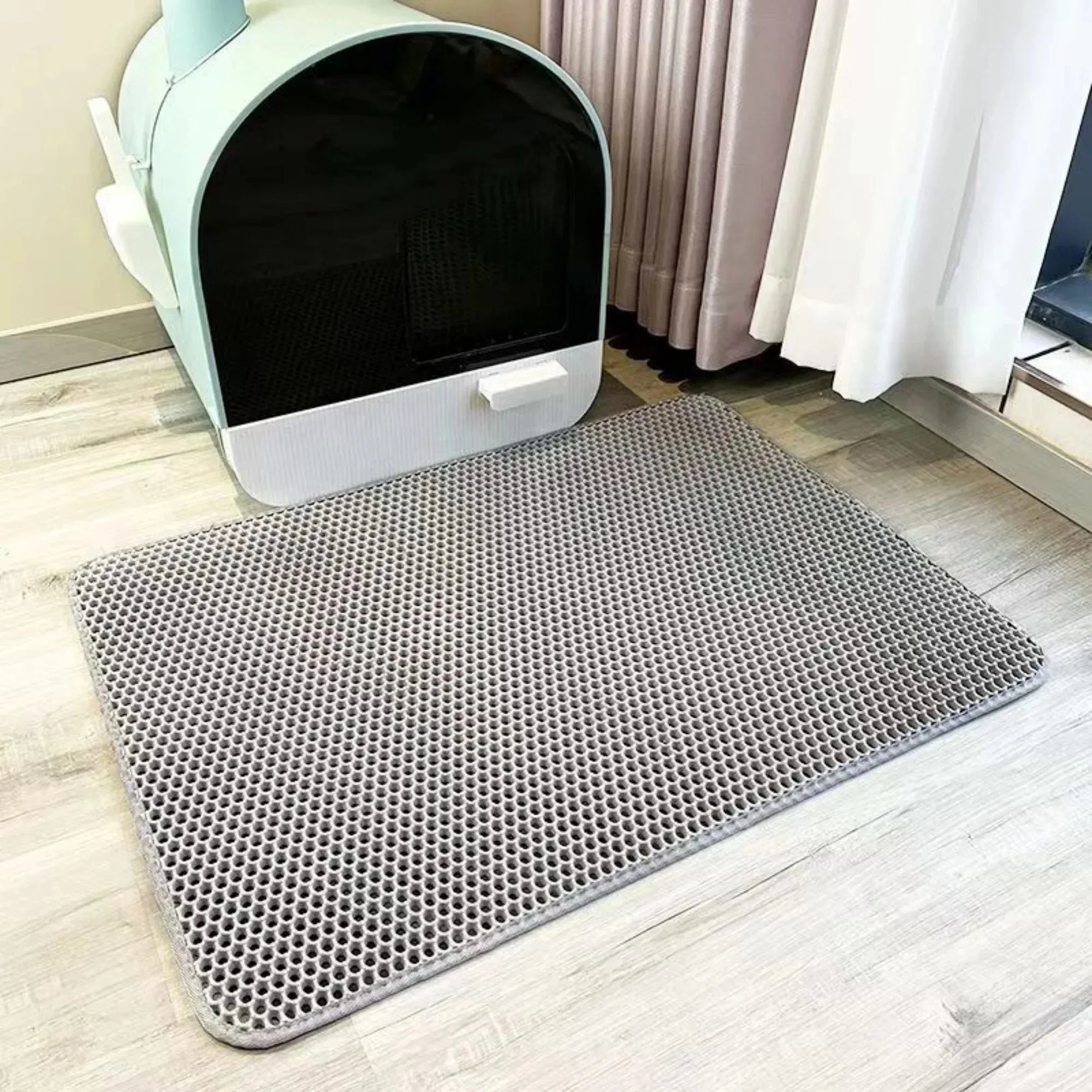 Cat litter mat with honeycomb holes, light gray, in front of a litter box