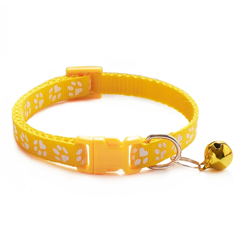 Yellow paw-print cat collar with plastic buckle and bell charm on a ring