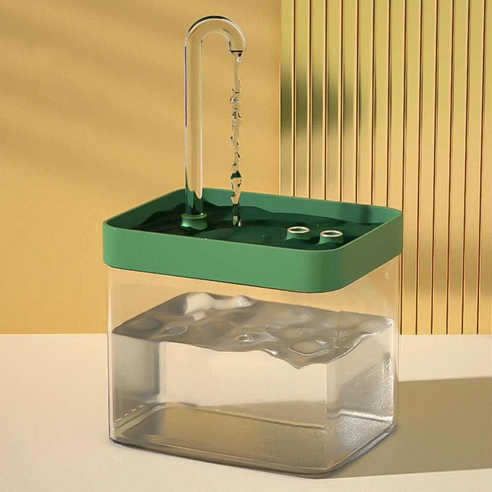 Transparent cat water fountain with green top tray, spout, and steady water flow into basin