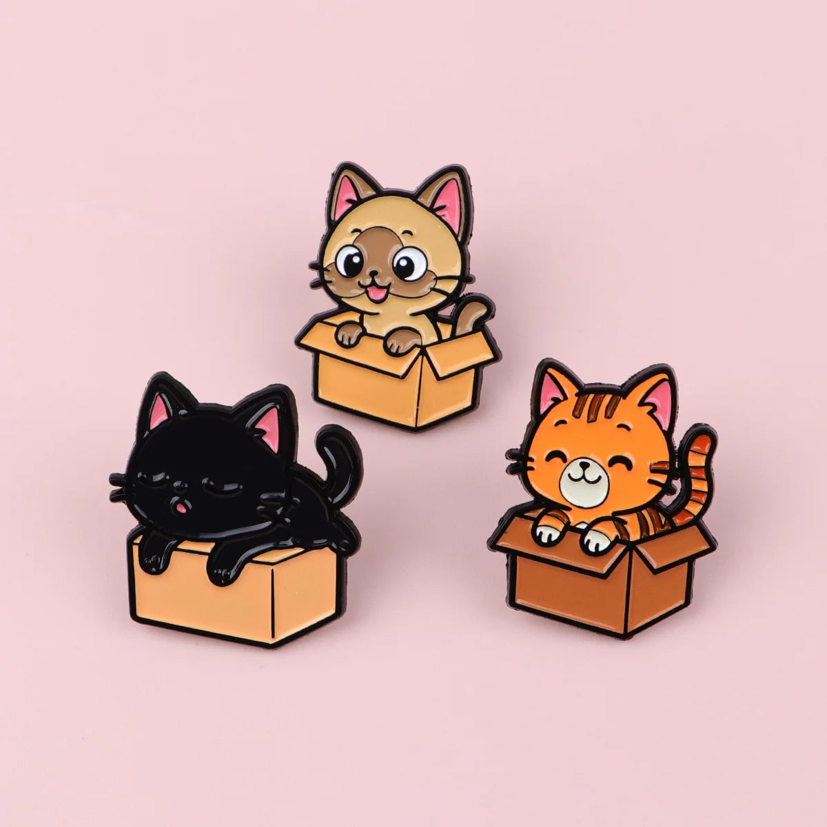 Enamel lapel pins featuring a tan cat and orange cat sitting in open boxes