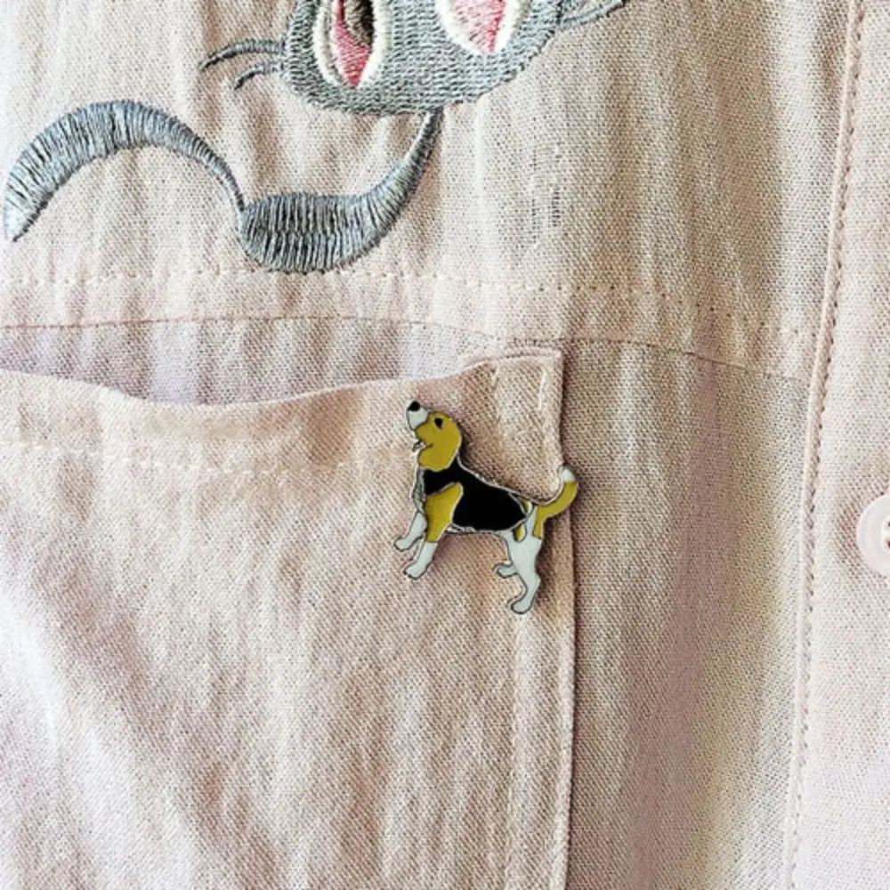 Cartoon beagle-style dog enamel pin on beige jacket pocket
