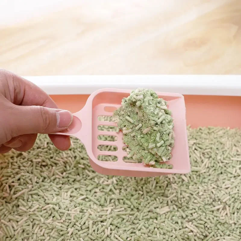 Cat litter sand scoop with pink grid tray held in hand