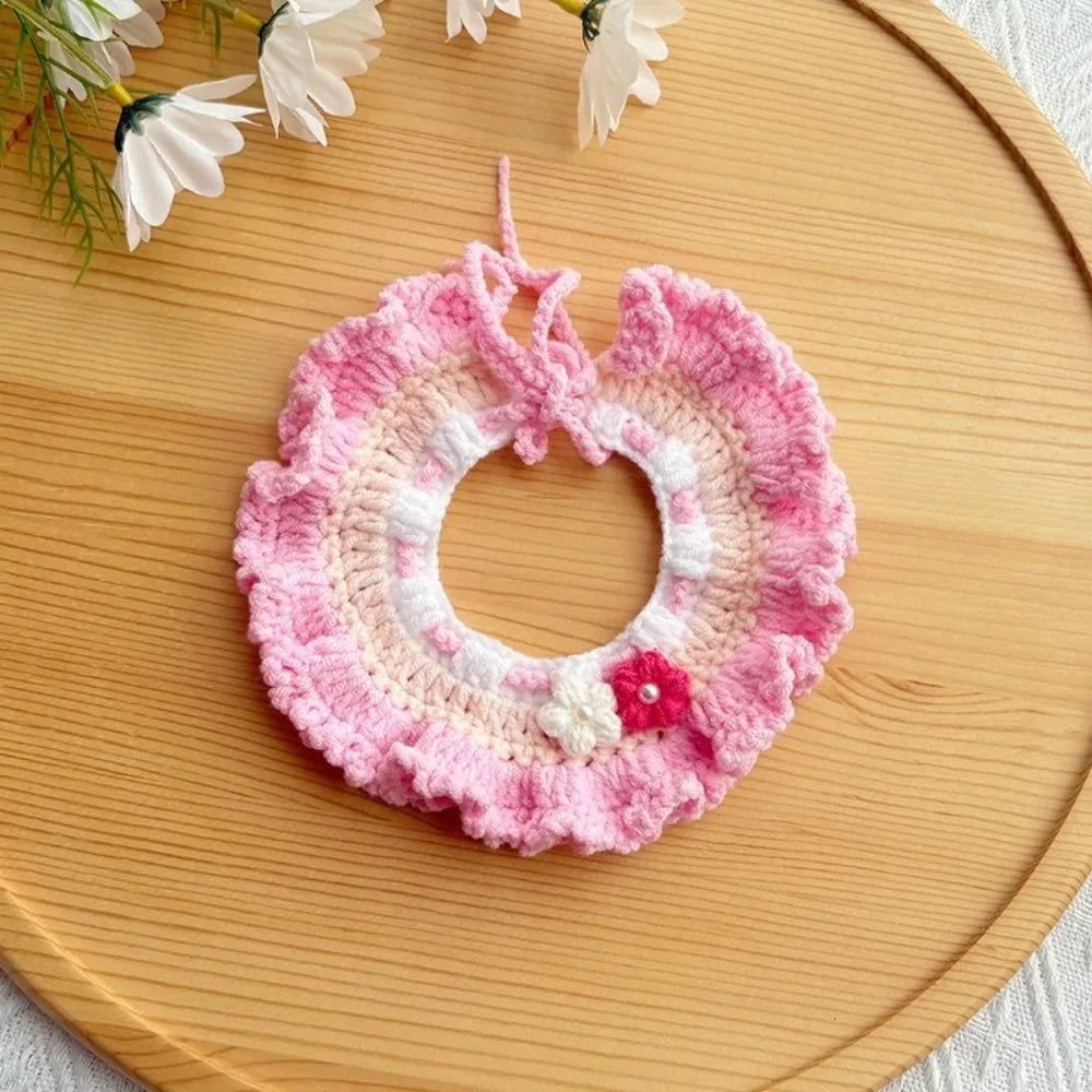 Pink crocheted pet scarf bib with white flower trim and red button accent