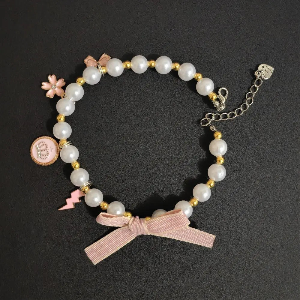 Cat pearl necklace collar with pink ribbon bow, round medallion, and dangling charms