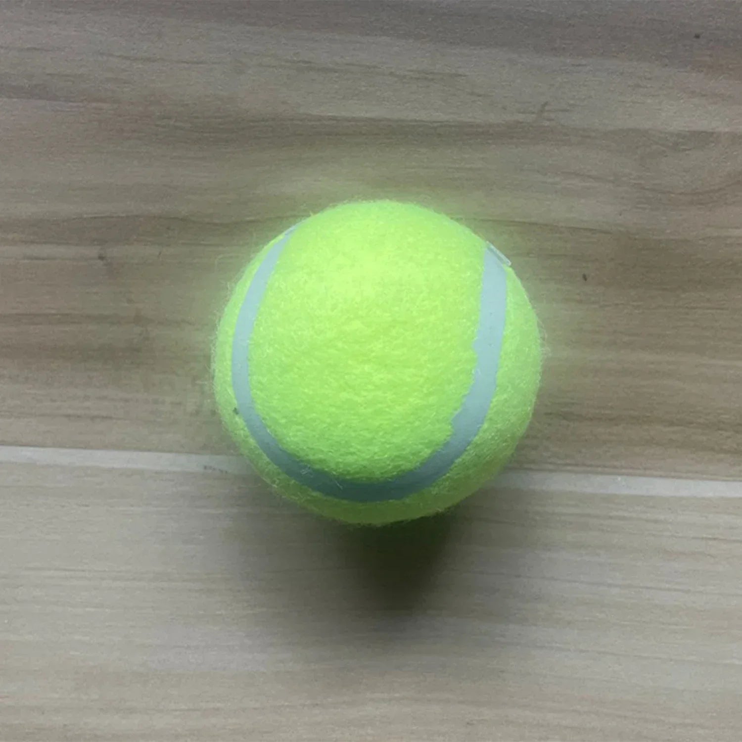 Single bright green tennis ball with yellow seam
