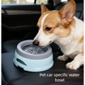 Light blue no-spill pet water bowl in a car, with dog drinking from the rim.