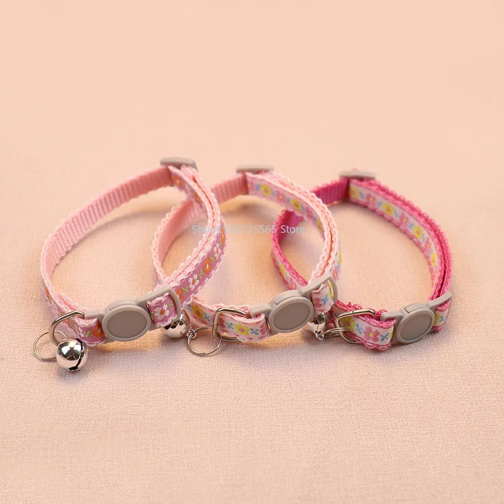 Pink floral cat collar with bell charm, round gray tag disc and metal rings.