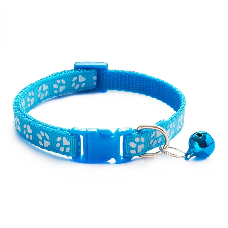 Light blue paw-print cat collar with plastic buckle and bell charm on a ring